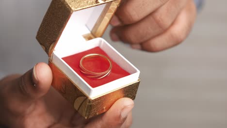 man opening a gold box with a ring inside