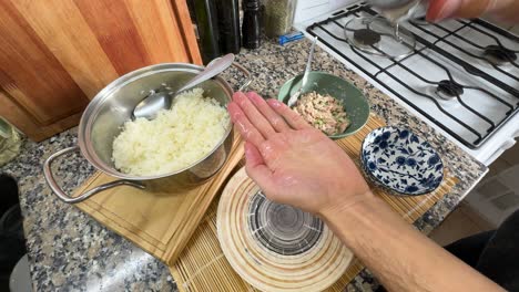 hands carefully shape seasoned rice to prepare onigiri - close up