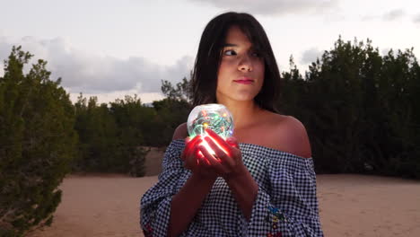 A-gorgeous-woman-sorceress-wandering-in-a-fantasy-landscape-with-a-magical-spiritual-orb-glowing-in-illuminated-light