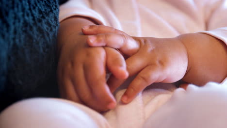 close up of baby girls hands as she is held by father