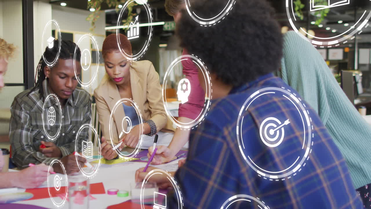 Animation of multiple digital icons against team of diverse colleagues discussing together at office