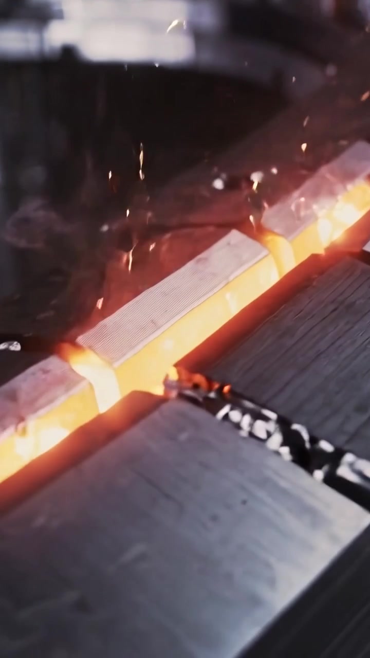 Video verticale: Billette incandescenti che emettono scintille e brillano sulla giunzione alla pressa, mentre il punzone contatta la giunzione e la matrice.