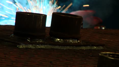 tilting up shot of a welder in full protective hse kit welding pipes at a factory with intense light and nice sparks from the welding operation