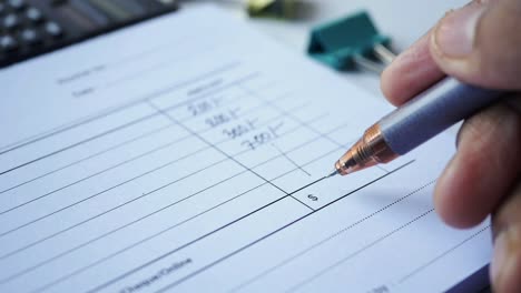 close-up of a hand writing on an invoice