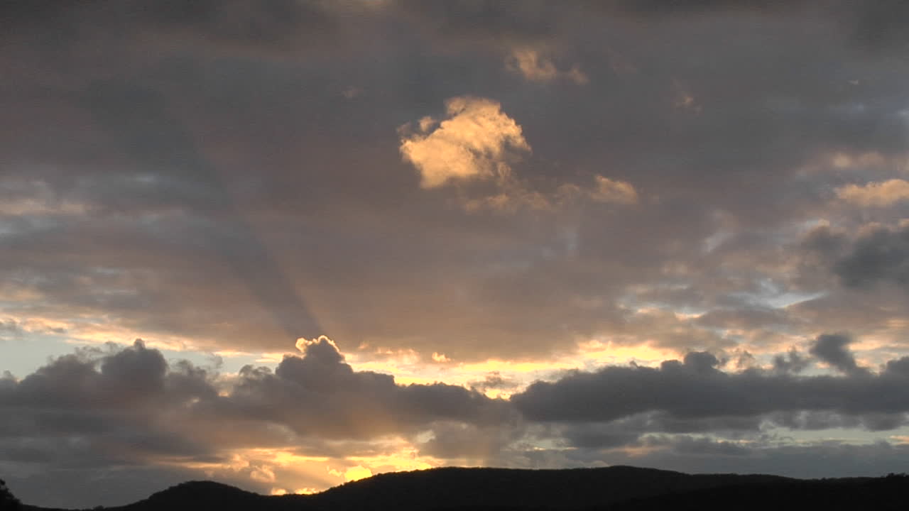 los rayos del sol se asoman a través de las nubes sobre una montaña