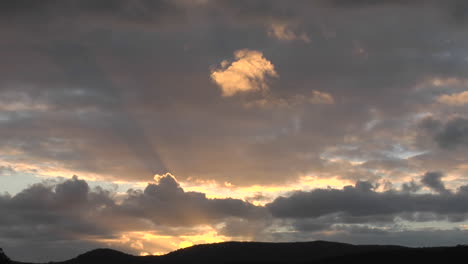 los rayos del sol se asoman a través de las nubes sobre una montaña