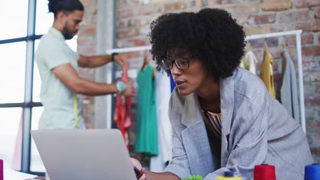 Diverse-male-and-female-fashion-designers-using-laptop-and-talking-on-smartphone