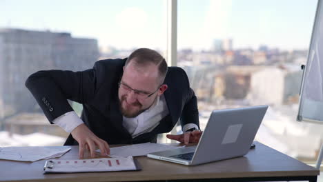 man doing funny faces sitting in front of laptop. mad businessman typing nervously with fingers on keyboard and looking to the sides. entrepreneur with insane face in office.