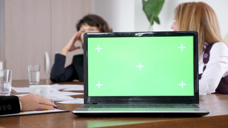 Laptop con green screen durante una riunione di lavoro