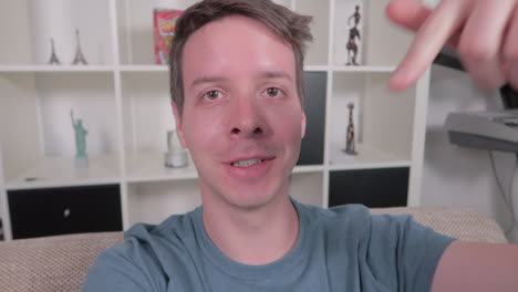 young adult caucasian male showing thumbs up, comment, vlogging at home in front of camera