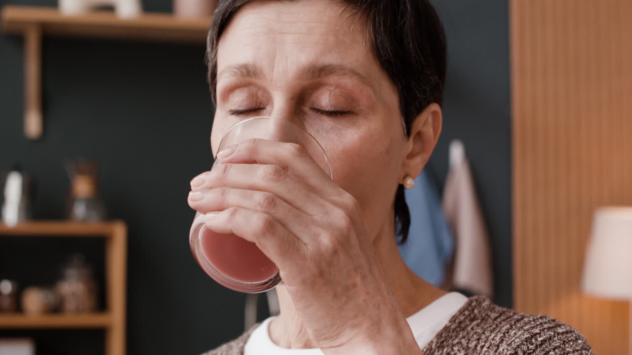 Elderly Woman Drinking from a Glass at Home