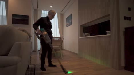 senior woman vacuums a floor using a laser attachment to see dust and debris on a hardwood floor