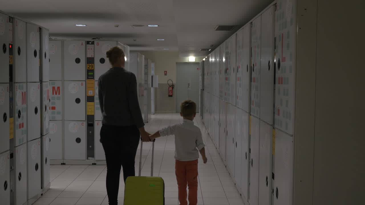 Woman and kid leaving suitcase in locker of luggage room