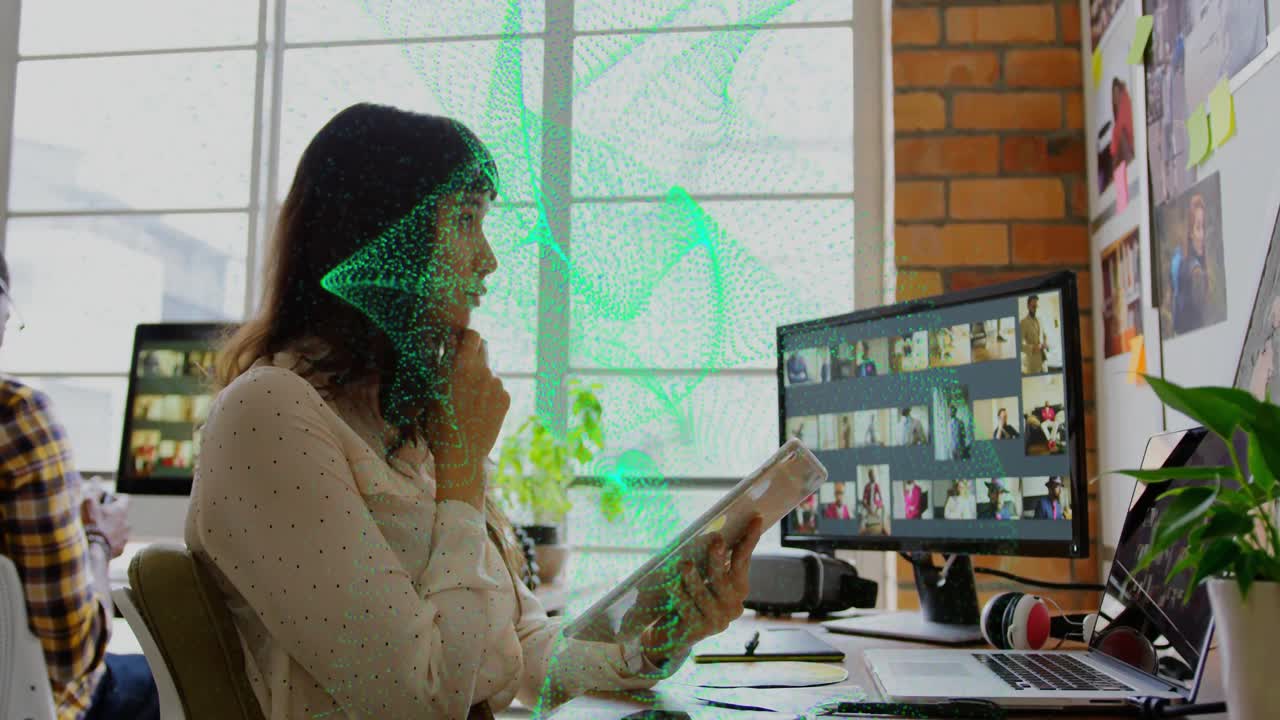 Mid-adult woman sitting at desk holding tablet and call grid icons floating above tech workspace