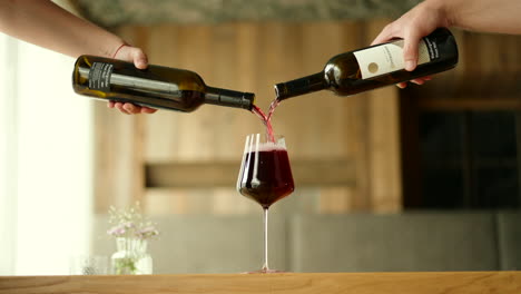 red wine being poured out of two bottles into one glass