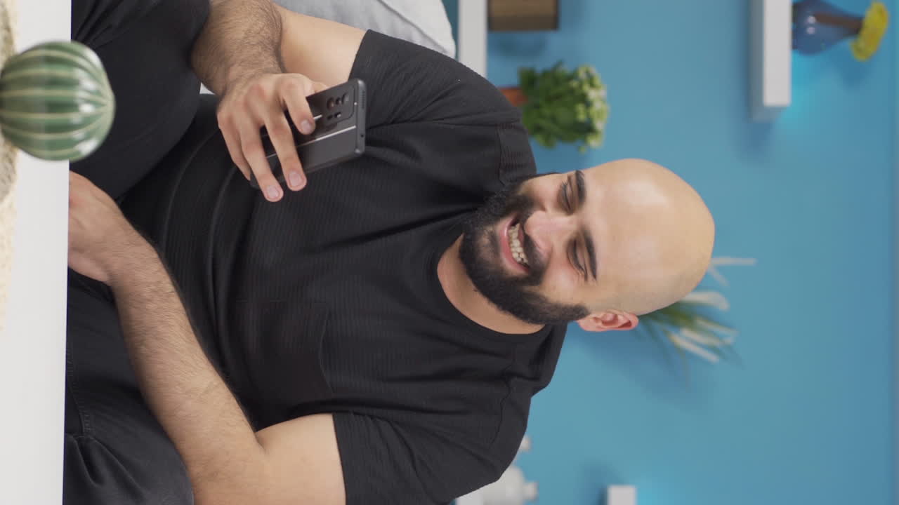 Vertical video of Man laughing at phone message.