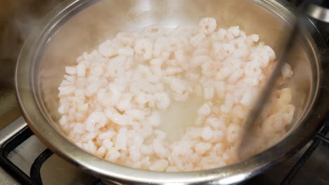 mezclar pequeños camarones frescos en una olla de plata humeante caliente