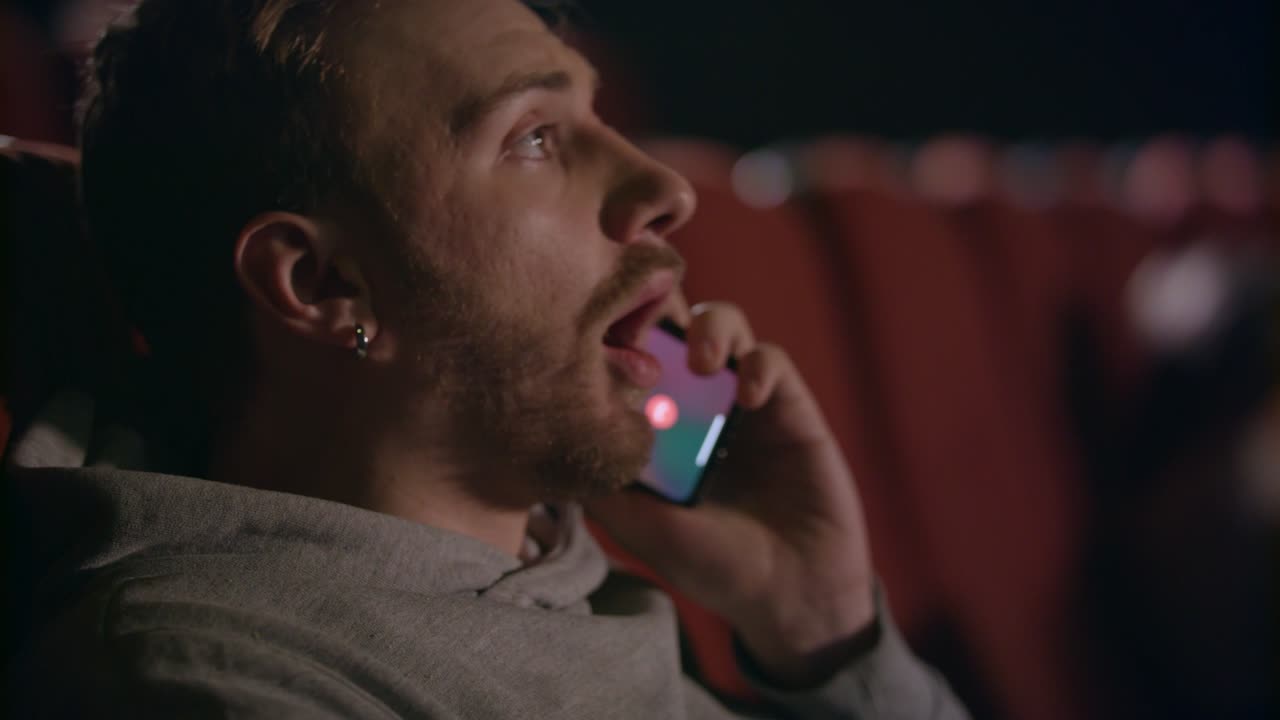 Ung mand taler i telefon i biografen. Tilskuer taler i telefon i biografen