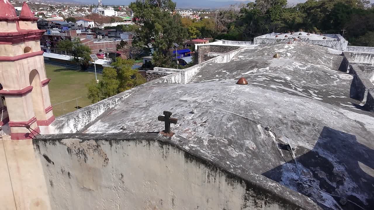 Aerial shot slowly reveals aged church roof surrounding urban landscape below