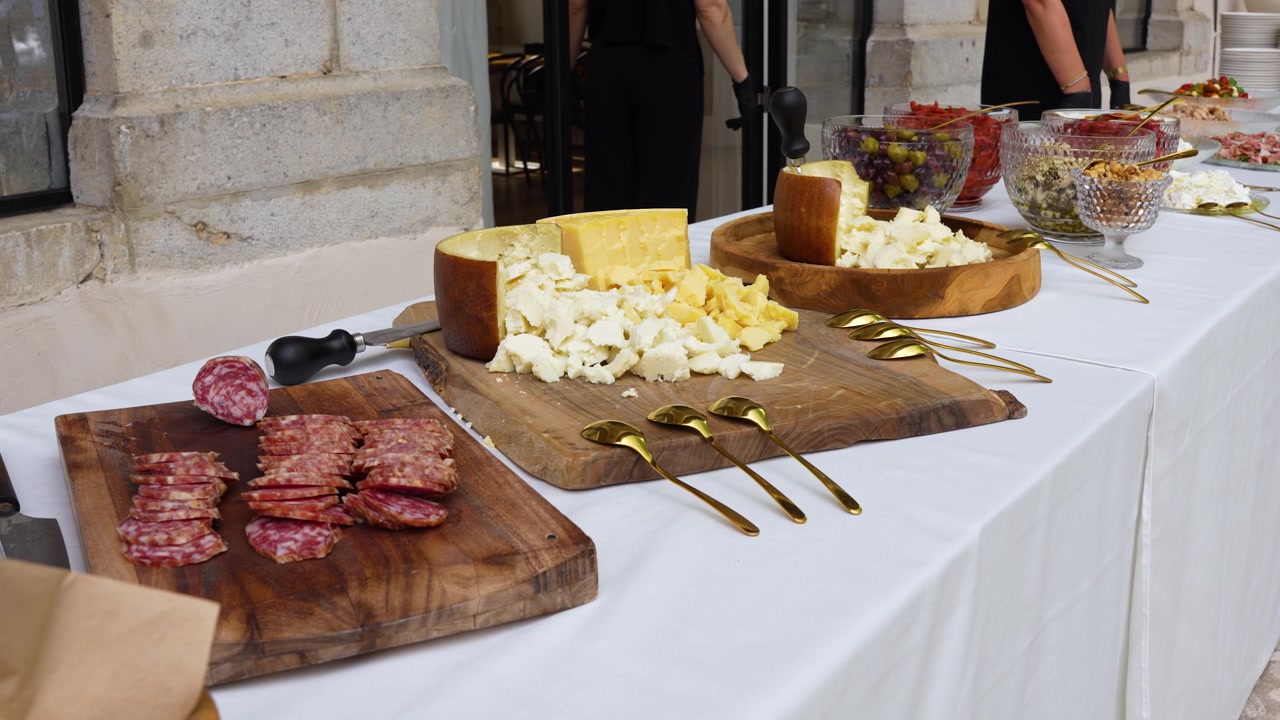 Tavolo da buffet gourmet con formaggi, salumi e insalate fresche di giorno, ripresa con gimbal, panoramica, inquadratura media