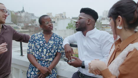 colleagues having conversation during break outdoors on urban rooftop