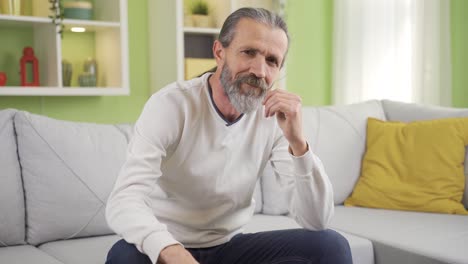 Reifer-Mann-Sitzt-Zu-Hause-Auf-Dem-Sofa-Im-Wohnzimmer-Und-Lächelt.