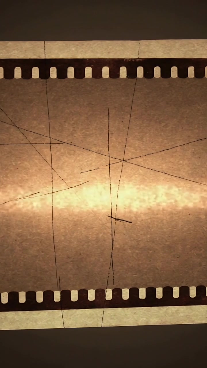 Video vertical: Luz cambiante causando pulsación de la película en una caja de luz, mostrando arañazos de perforaciones y una marca en X.