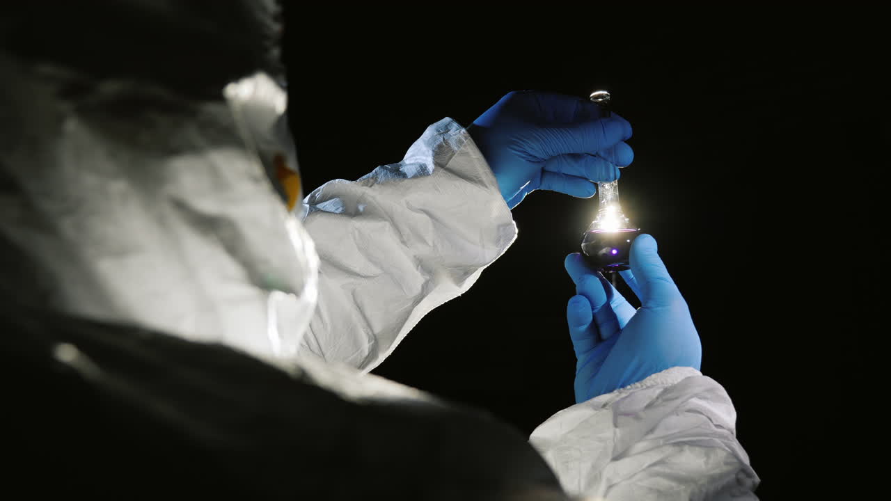 científico con traje protector mira un tubo de ensayo con una droga