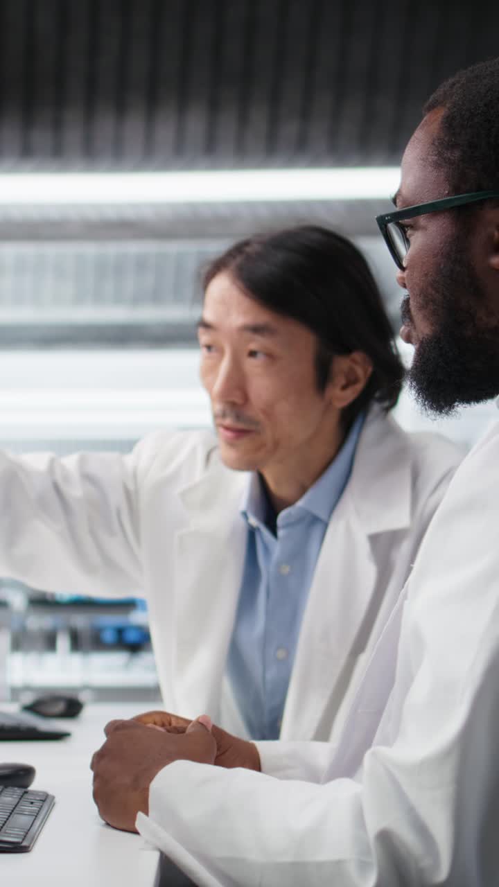 Vertical video Multiracial engineers using scientific gear in research facility