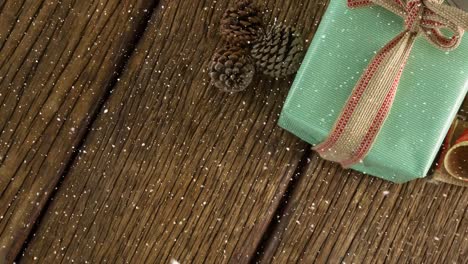 Fallender-Schnee-Mit-Weihnachtsgeschenkdekoration-Auf-Holz