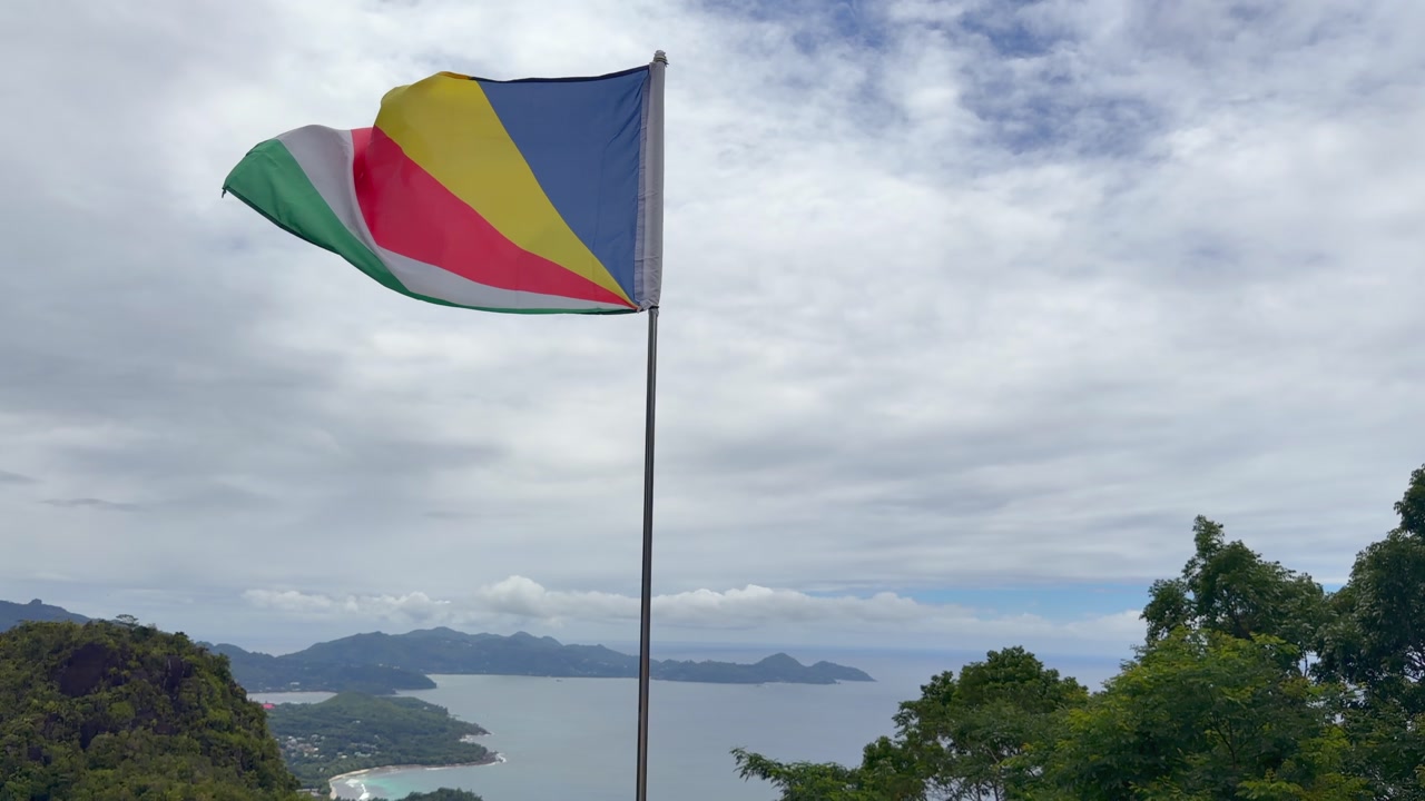 Seychelles flag floating above hill, from the national park, panoramic view of the western coast, Mahe, Seychelles 60fps 002