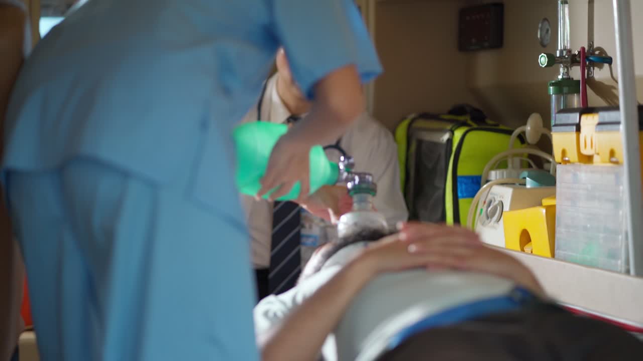 EMS paramedics team help injured patient in the ambulance during transfer to hospital. Hand holding a resuscitation bag help for breathing in emergency case. Accident and healthcare concept