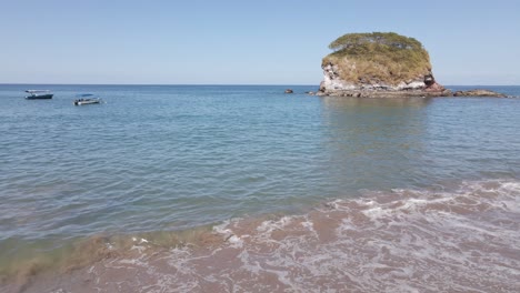 Paneo-Lento-Hacia-Adelante-Sobre-La-Costa-En-La-Playa-Real-Hacia-Dos-Botes-Y-Una-Pequeña-Formación-Rocosa