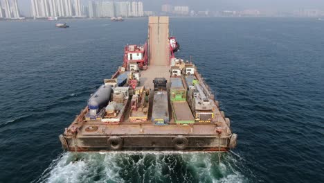 Lastkahn-Beladen-Mit-Betonmischern,-Die-Von-Einem-Schlepper-In-Der-Bucht-Von-Hongkong-In-Den-Hafen-Gezogen-Werden,-Luftbild