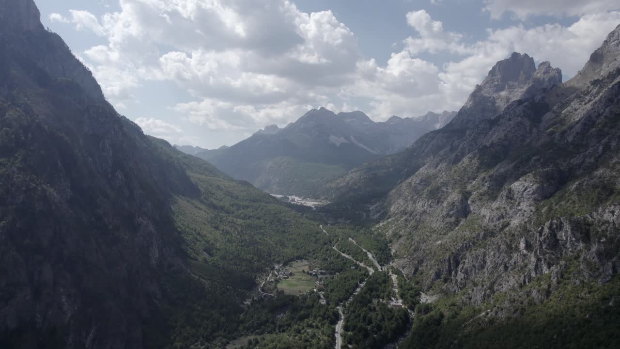 video de drone de avion frontal descendiendo entre las colinas del valle de valbona, albania, vuela muy cerca del terreno apreciando la belleza de las casas y arboles de la zona