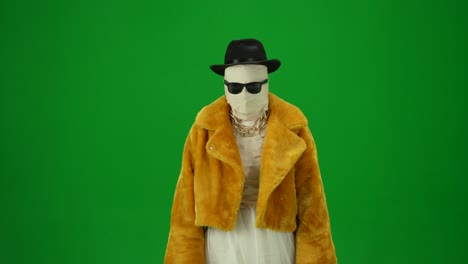 glamorous mummy in orange coat hat and sunglasses walking gracefully towards the camera as if it's