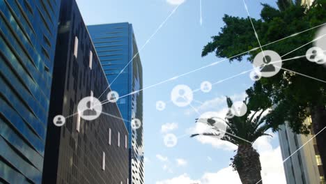 animation of network of profile icons against low angle view of tall buildings and blue sky