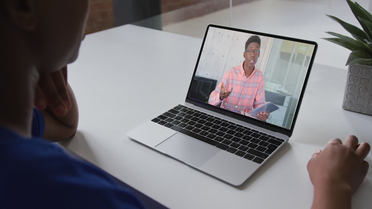 Mid section of african american woman having a video call with male colleague on laptop at office
