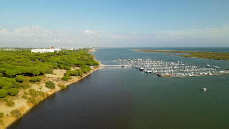 Vuelo-Aéreo-Sobre-El-Muelle-Con-Muchos-Yates,-Veleros,-Barcos-En-El-Río-Piedras-Puerto-Marina-El-Rompido,-España-En-Verano