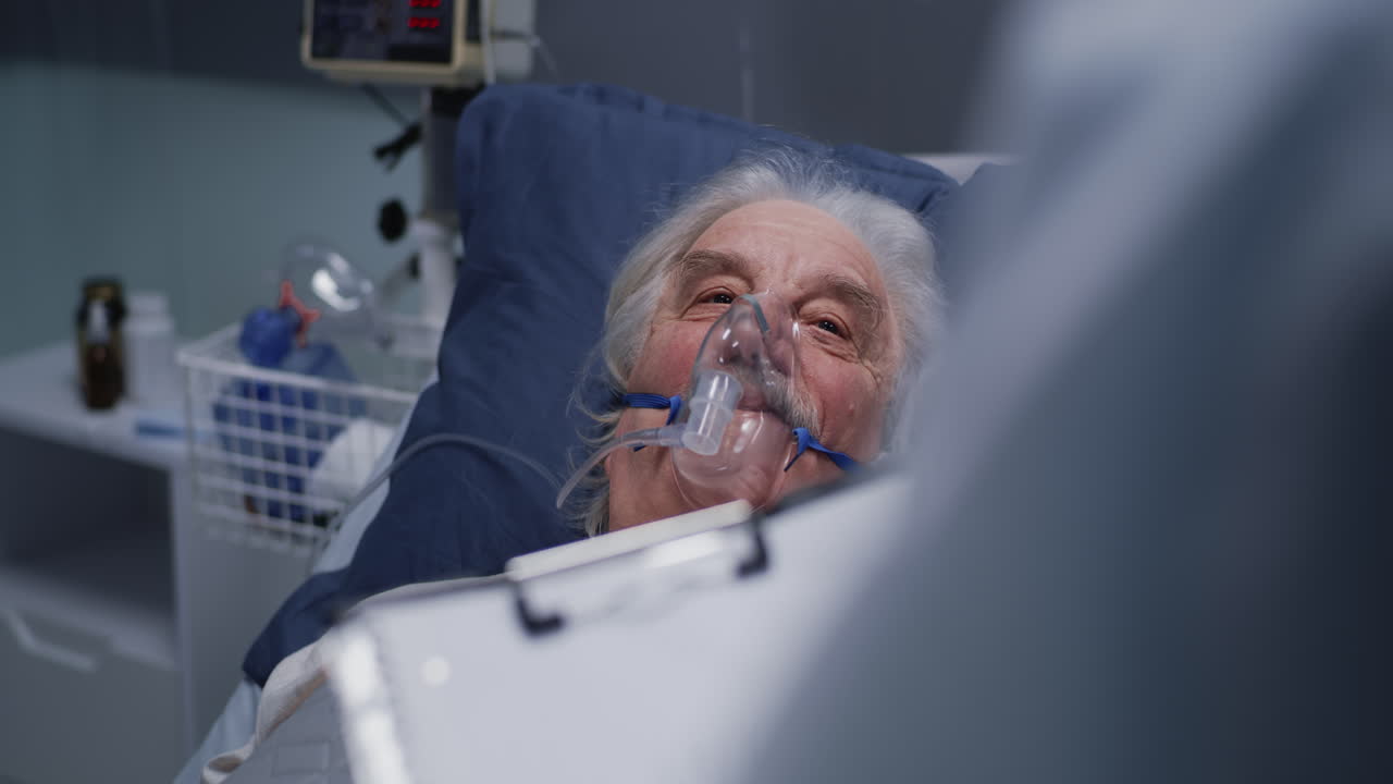 An elderly patient in a hospital bed expressing gratitude to a medical professional