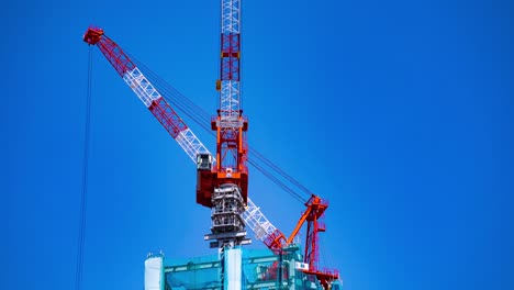 a time lapse of back and forth crane behind the blue sky at the under construction in tokyo zoom