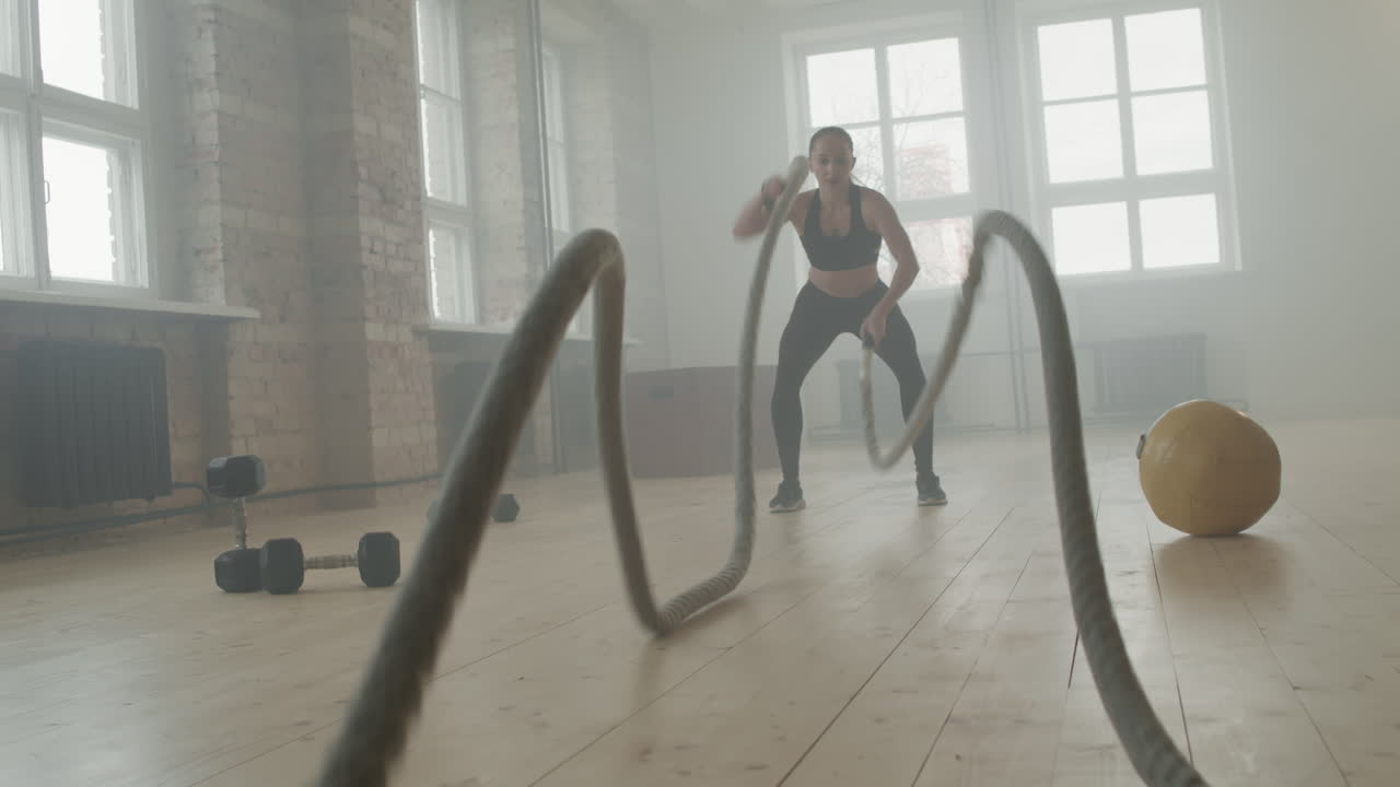 Girl Training With Battle Rope In Gym