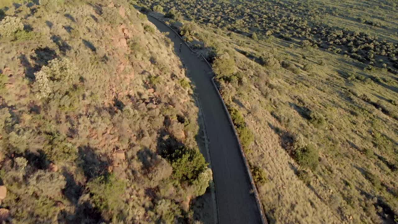 언덕 푸른 나무와 푸른 들판을 오르는 자전거 타는 사람들과 함께 언덕 아래로 공중