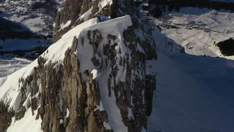 aerial view flying along a rocky and snowy mountain ridge in the french alps near la clusaz in winter