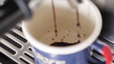 movimiento lento de cerca de la máquina de café espresso goteando café en la taza de café azul