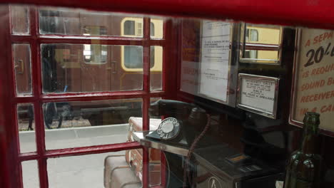 una cabina telefónica británica roja de la década de 1940 con un teléfono rotatorio negro en el interior durante la segunda guerra mundial