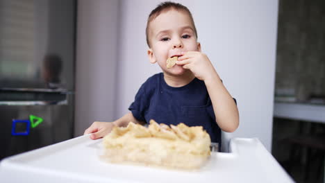 baby boy eating cake using no hands. lovely baby enjoying sweets. close up. blurred backdrop.