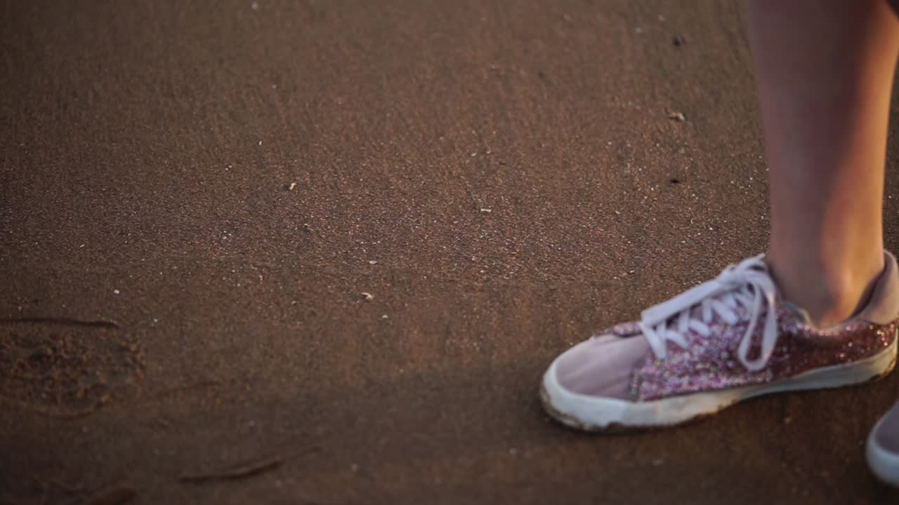 Persona che cammina sulla spiaggia indossando scarpe glitterate