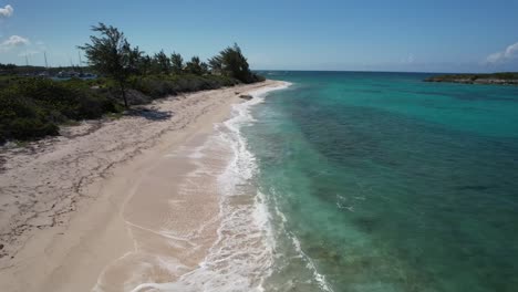 white sand beach and turquoise water of the ocean in bahamas - aerial forward
