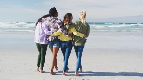 Happy-group-of-diverse-female-friends-having-fun,-walking-along-beach